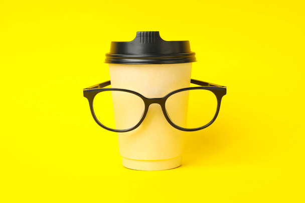 Copa de papel con gafas sobre fondo amarillo - Foto, imagen