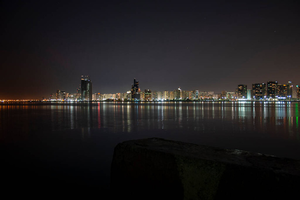 Μια νυχτερινή γραμμή του ορίζοντα του Abu Dhabi Corniche ληφθεί από το μεγάλο κοντάρι σημαία - Φωτογραφία, εικόνα