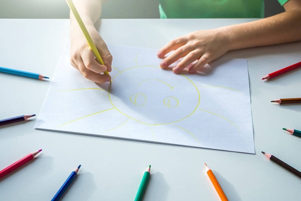 Kid draws sun with pencils. Child's creativity and art. Preschooler gets drawing skills in kindergarten. Children Protection Day - Фото, изображение