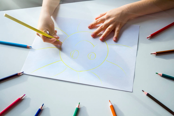 Kid draws sun with pencils. Child's creativity and art. Preschooler gets drawing skills in kindergarten. Children Protection Day - Foto, Imagem