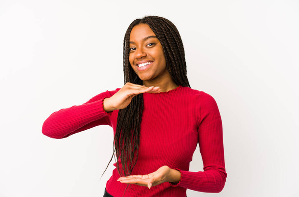 Jonge Afro-Amerikaanse vrouw geïsoleerd houden iets met beide handen, product presentatie. - Foto, afbeelding