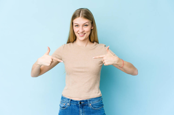 Nuori blondi nainen eristetty sinisellä taustalla henkilö osoittaa käsin paita kopioi tilaa, ylpeä ja luottavainen - Valokuva, kuva