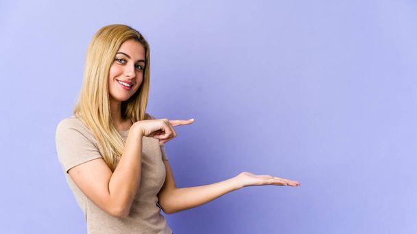 Young blonde caucasian woman excited holding a copy space on palm. - Фото, зображення
