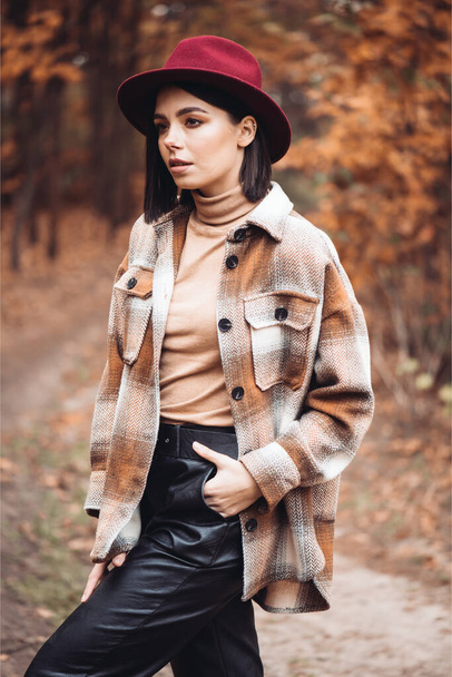 Young woman fashionably dressed in a dry autumn forest - Foto, imagen