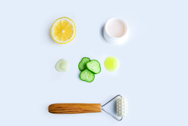 Flat lay pattern from cucumber slices and drop of facial mask, face gel, roller massager and container with cream. Cleansing and moisturizing cucumber cosmetics. Natural organic beauty products - 写真・画像