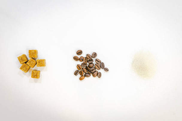 seis terrones de azúcar con un puñado de granos de café aislados y azúcar refinada. Concepto de fuente de adicción y elección del azúcar. - Foto, imagen