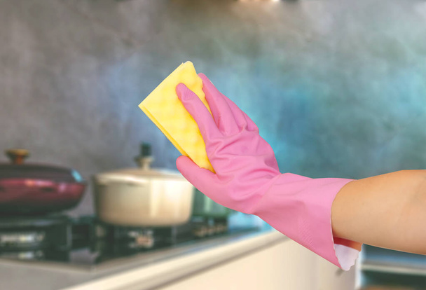 nettoyer la cuisine et les ustensiles de cuisine. main dans le gant rose avec éponge jaune a été nettoyé cuisine, assiette, gamme, casserole, casserole, cuisinière - Photo, image
