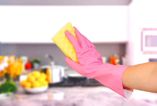 καθαρισμός της κουζίνας και των μαγειρικών σκευών. χέρι σε ροζ γάντι με κίτρινο σφουγγάρι έχει καθαριστεί από κουζίνα, πιάτο, εύρος, τηγάνι, κατσαρόλα, φούρνο - Φωτογραφία, εικόνα