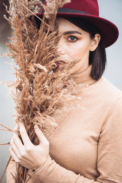 Outdoor fashion photo of young beautiful lady in autumn landscape with dry grass. Knitted sweater, wine lipstick. Warm Autumn. - Foto, immagini