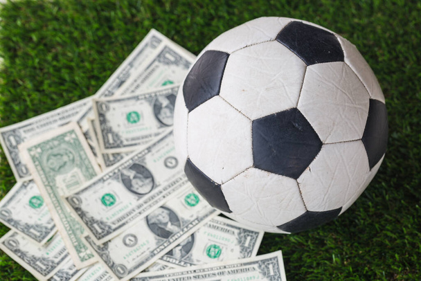  μπάλα ποδοσφαίρου με δολάριο νομοσχέδιο στο γρασίδι φόντο - Φωτογραφία, εικόνα