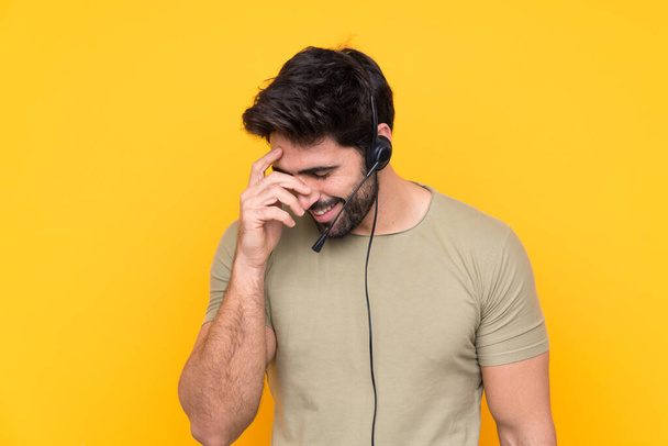 Telemarketer man working with a headset over isolated yellow background laughing - Foto, Imagem