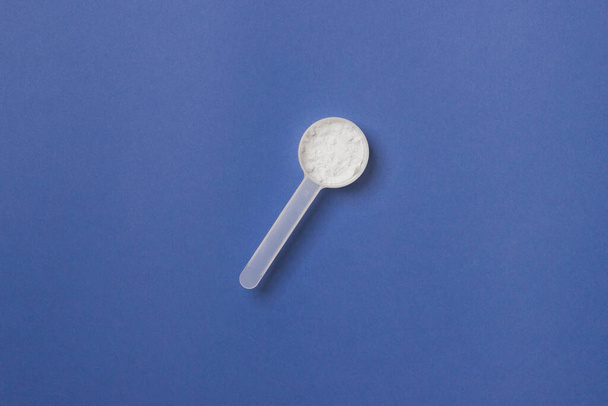 measure spoon on blue colored paper background. - 写真・画像
