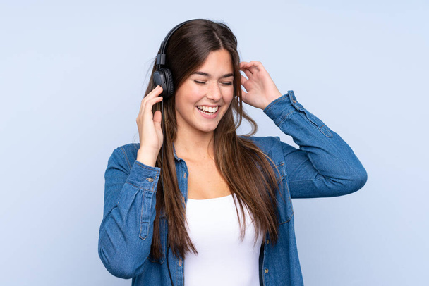 Nastoletnia Brazylijka słucha muzyki na odizolowanym niebieskim tle - Zdjęcie, obraz