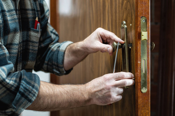 Close-up. Carpenter installs the lock handle of a wooden door. Construction industry.  - Photo, Image