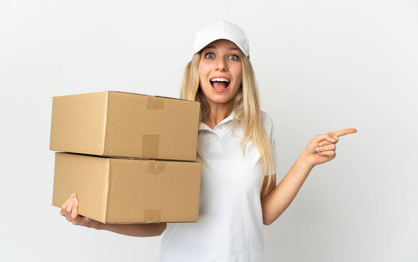 Young delivery woman isolated on white background surprised and pointing finger to the side  - Photo, Image