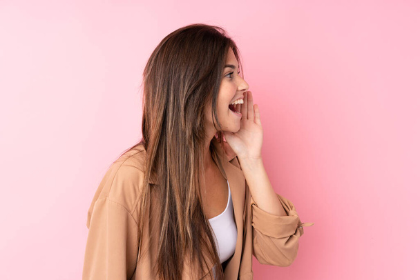 tiener Braziliaanse meisje over geïsoleerde roze achtergrond schreeuwen met mond wijd open - Foto, afbeelding