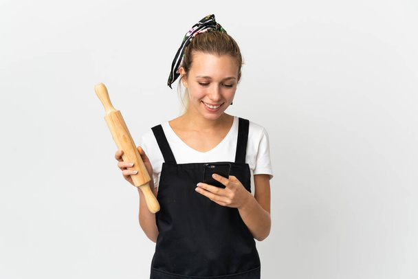 Молода жінка тримає прокатний штифт ізольовано на білому тлі, надсилаючи повідомлення з мобільним
 - Фото, зображення