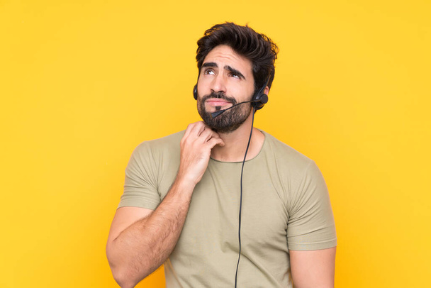 Hombre telemarketer trabajando con un auricular sobre un fondo amarillo aislado pensando en una idea - Foto, Imagen