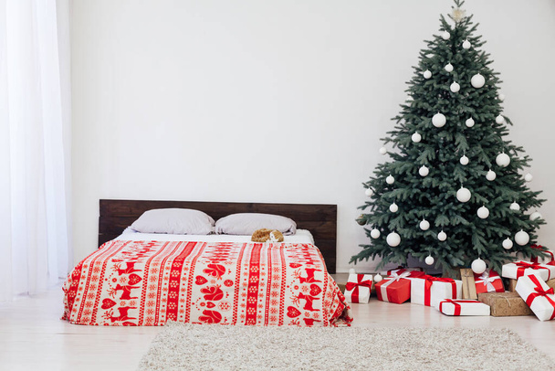 Pino árbol de Navidad con regalos junto a la cama en la decoración del dormitorio año nuevo fondo blanco 2021 2022 - Foto, imagen