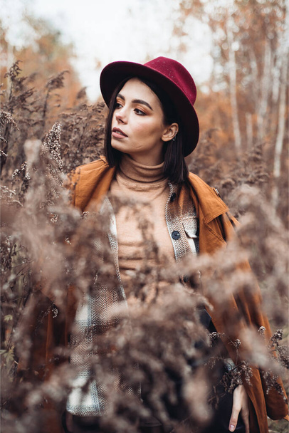 Beautiful elegant woman standing in a park in autumn - Foto, Bild