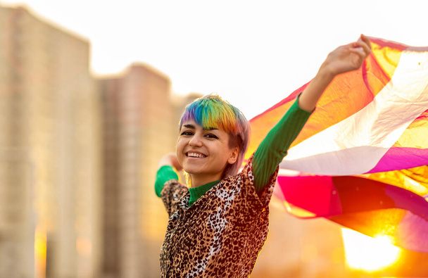 Πορτρέτο του ευτυχούς μη δυαδικού προσώπου κυματίζει υγρό σημαία φύλου - Φωτογραφία, εικόνα