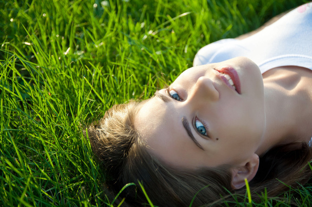 jonge brunette liggen op het gras - Foto, afbeelding