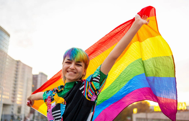 Retrato de una persona no binaria feliz ondeando la bandera del arco iris - Foto, imagen