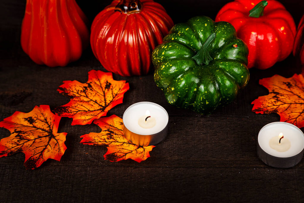Halloween. Pumpkins glow in the dark. Still life with pumpkins, candles and autumn leaves on a wooden background - Photo, image
