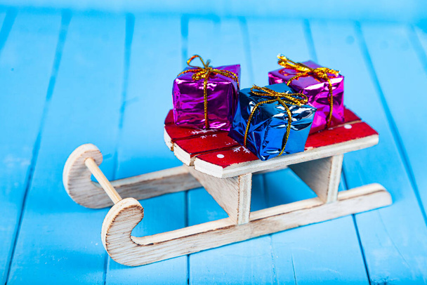 Sleds with gifts on a blue wooden background. Christmas presents. - Fotografie, Obrázek