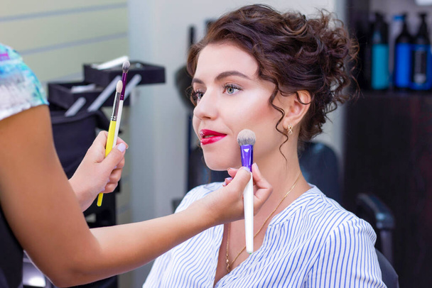 Make up artist applies a light layer of matte powder using a professional makeup brush. girl at makeup artist - Foto, Imagen