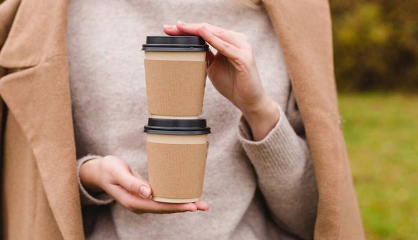 Женщина держит две бумажные чашки кофе. Концепция вывоза или доставки. Принято. Осенний образ жизни. Место для вашего текста или логотипа на кружке - Фото, изображение