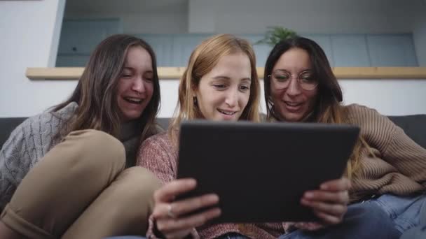 Група друзів жінка читає планшет і сміється у вітальні вдома. Концепція дружби та технологій
. - Кадри, відео