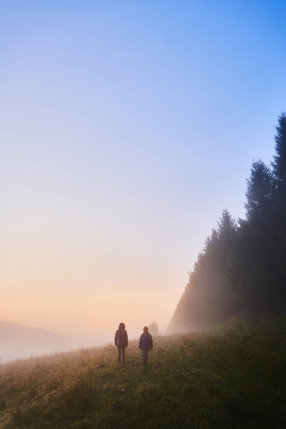 Sisli bir sabahta ağaçların arasında yürüyüşe çıkan iki çocuk. Polonya 'daki Beskid Hills manzarası. - Fotoğraf, Görsel