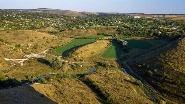 Moldovan luonto, laakso virtaava joki, rinteet harva kasvillisuus, kylä täynnä vehreyttä lähellä - Valokuva, kuva