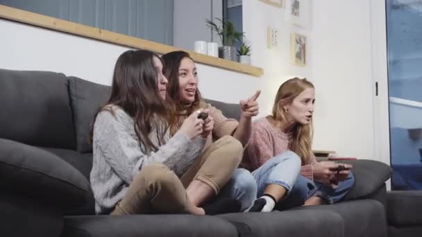 女性の友人のグループは、リビングルームでソファに座って自宅でビデオゲームをプレイ. - 映像、動画