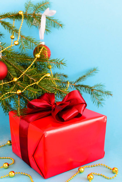 Gift in a big red box with a bow for Christmas and New Years with a Christmas tree on a blue background. - Photo, Image