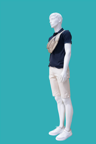 Полноразмерный мужской манекен, одетый в модную летнюю одежду, выделенный на зеленом фоне. Нет фирменных наименований или объектов авторского права. - Фото, изображение