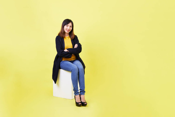 attractive young Asian woman sitting on the blank empty box on yellow background For job hunting ideas - Фото, зображення