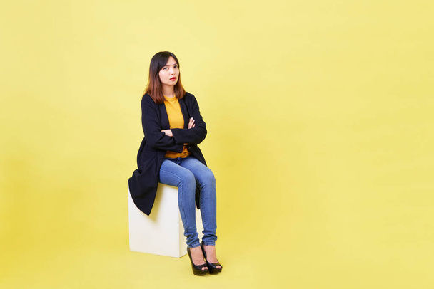 atractiva mujer asiática joven sentada en la caja vacía en blanco sobre fondo amarillo Para ideas de búsqueda de empleo - Foto, Imagen