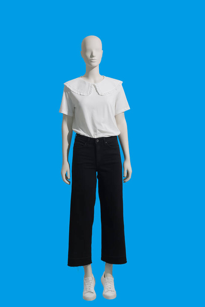 Full length γυναικεία κούκλα ντυμένη με λευκή μπλούζα και μαύρο τζιν. Απομονωμένο σε μπλε φόντο. Δεν υπάρχουν εμπορικά σήματα ή αντικείμενα πνευματικών δικαιωμάτων. - Φωτογραφία, εικόνα