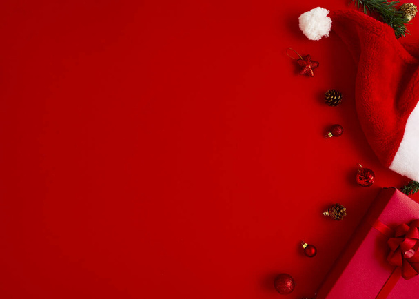 2020 Πρωτοχρονιά Χριστούγεννα παρουσιάζει Σάντα καπέλο με δώρα και χριστουγεννιάτικα στολίδια σε ένα κόκκινο χαρτί φόντο αντίγραφο χώρο. - Φωτογραφία, εικόνα