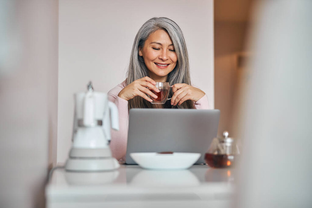 Fröhliche Frau nutzt modernen Laptop zu Hause - Foto, Bild