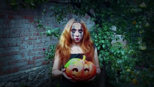 Joven mujer sexy bruja sosteniendo una calabaza tallada, fondo de Halloween - Metraje, vídeo