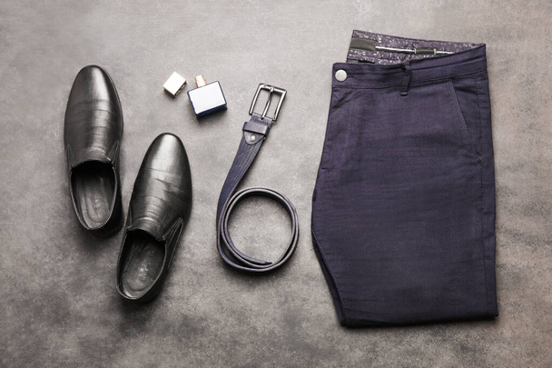 Klasyczne niebieskie męskie spodnie z czarnymi skórzanymi butami i paskiem na czarnym tle. Odzież męska. - Zdjęcie, obraz