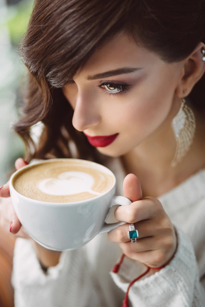 Молода дівчина п'є каву в модному кафе
 - Фото, зображення