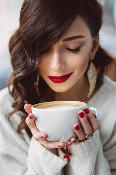 Nuori tyttö juo kahvia trendikkäässä kahvilassa
 - Valokuva, kuva