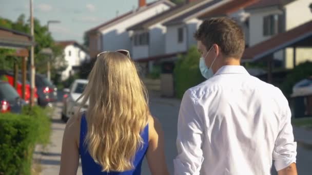 CLOSE UP Millennial couple kissing through masks as they walk around the suburbs - Záběry, video
