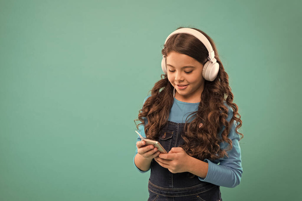 small child make play list on smartphone. small girl hold mp3 player. choosing favorite song. e-learning in modern life. schoolgirl use new technology. kid listen music in headphones. copy space - Photo, Image