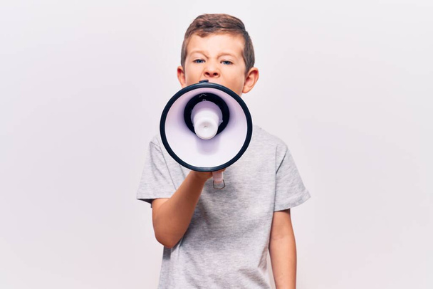 Kızgın suratlı sevimli beyaz bir çocuk. İzole edilmiş beyaz arka planda duran megafon kullanarak yüksek sesle bağırmak - Fotoğraf, Görsel