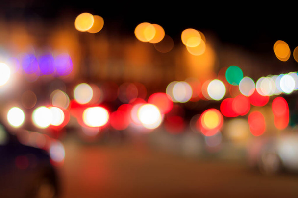 Zamglone światła reflektorów samochodów i latarni w mieście nocy. Streszczenie jasny bokeh. - Zdjęcie, obraz